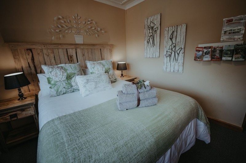 Hard Pear double ensuite room with rustic wooden headboard and protea cushions